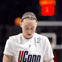 a woman wearing a white shirt that says uconn looks down