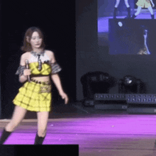 a woman in a yellow dress is dancing on a stage