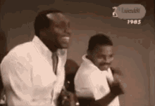 a couple of men are standing next to each other and laughing in a black and white photo .