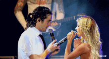 a woman singing into a microphone next to a man in a white shirt