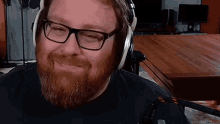 a man with a beard and glasses wearing headphones is smiling .