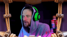 a man wearing headphones and a hoodie is sitting at a desk .