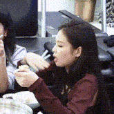 a woman is sitting at a table eating food from a bowl with chopsticks .