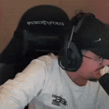 a man wearing headphones and a hat is sitting in a chair with the word dxracer on it