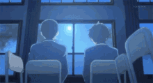 two men are sitting in chairs looking out of a window .