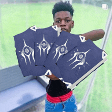 a young man is holding a stack of blue cards with a white design