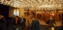 a group of men in suits are dancing in a room with a lot of lights .