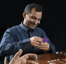 a man is smiling while playing a game of cards .