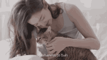 a woman is holding a cat in her arms and the cat 's age is 20