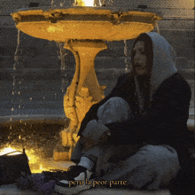 a woman is sitting in front of a fountain with the words pero la peor parte written below her