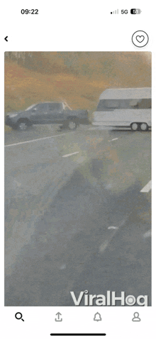 a phone screen shows a truck pulling a trailer on the road