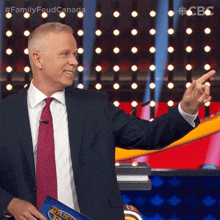 a man in a suit and tie holds a family feud game