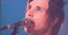 a close up of a man singing into a microphone on a stage .