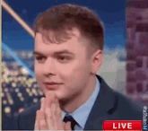 a man in a suit and tie is making a funny face while talking on a live television show .