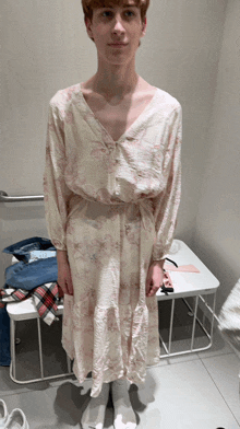 a young man in a white dress is standing in a changing room