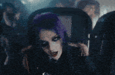 a woman with purple hair is holding a microphone and a mirror