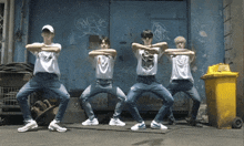 a group of young men are dancing in front of a blue wall with graffiti on it including one that says rnp