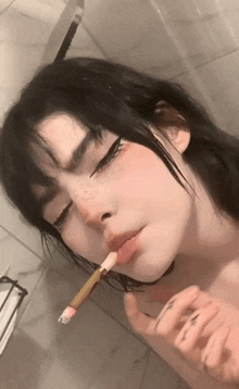 a woman with a brush in her mouth looks at herself in the mirror