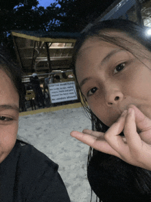 two girls are posing for a picture in front of a sign that says " keep the bound glass "
