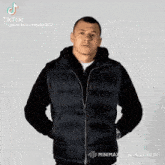 a man wearing a black vest is making a funny face with tiktok written above him