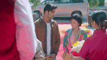 a man and woman are standing next to each other in front of a car