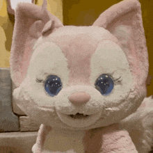 a pink and white stuffed animal with blue eyes