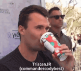 a man drinking from a cup with the name tristan jr written on it