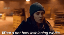 a woman in a beanie is talking to another woman in a dark room .