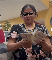 a woman wearing sunglasses and a gold chain is holding money