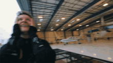 a blurry picture of a man standing in a hangar with a plane in the background