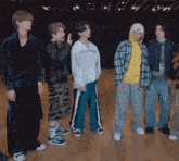 a group of young men are standing next to each other on a wooden floor in a room .