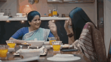 two women are sitting at a table with bowls of food