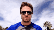 a man wearing sunglasses and a blue shirt with a nike logo