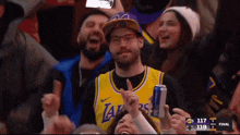 a man wearing a lakers jersey holds a can
