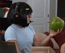 a person wearing headphones holds a watermelon in their hand