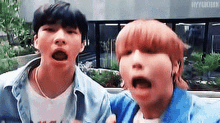two young men are standing next to each other with their mouths open and making funny faces .