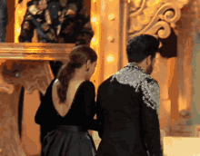 a man and a woman are standing next to each other in front of a mirror