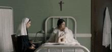 a nun sits in a chair next to a woman in a hospital bed