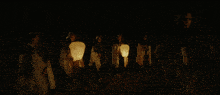 a group of people are holding lanterns in a dark room