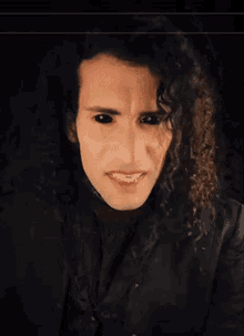 a man with curly hair and black eyes is pointing