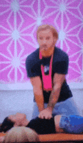 a man is giving a woman a massage in front of a pink background .