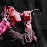 a man is singing into a microphone while holding a guitar on a stage .
