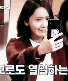 a woman is taking a picture of herself with a cell phone with korean writing on it
