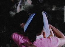 a woman in a pink sweater is hugging another woman in a blue headband