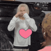 a woman in a white sweater with a pink heart in front of her