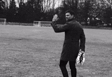 a man in a trench coat holds a pair of soccer cleats