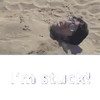 a man is buried in the sand with the words " i 'm stuck " written below him