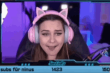a woman wearing pink headphones with cat ears is sitting in a chair on a computer screen .
