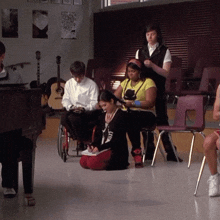 a group of people are sitting around a piano and chairs including a woman in a wheelchair