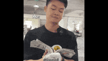 a man is holding a stack of money and says " me "